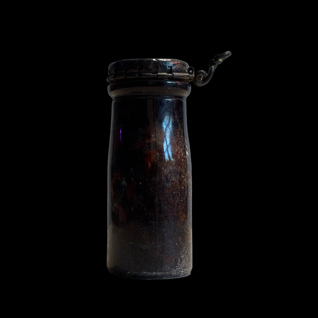 Small glass jar with a metal lid on a black background