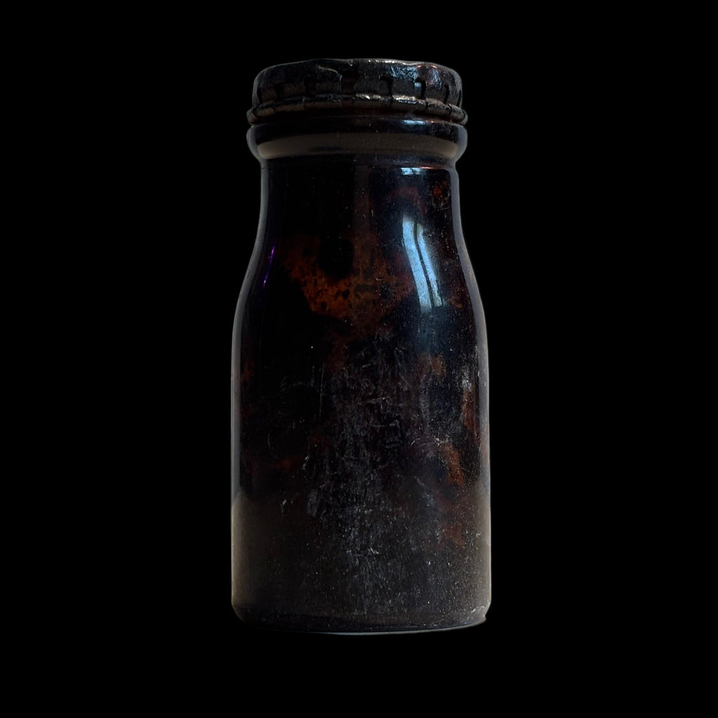 Vintage glass bottle with a dark tint on a black background
